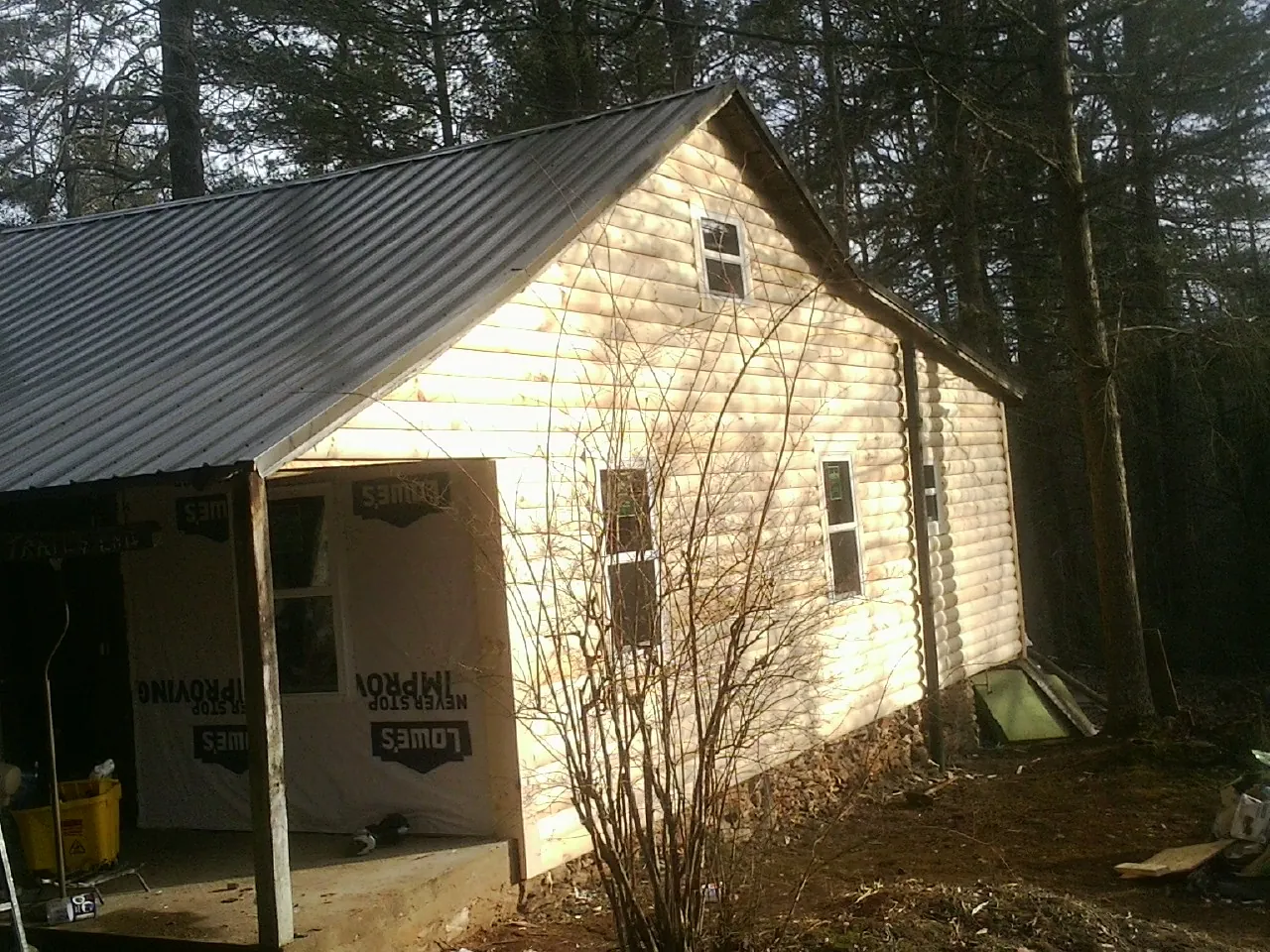 Log siding gable end under a dark metal roof edge in Cottondale