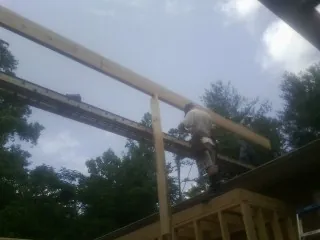 Carpenter setting a ridge beam over a new addition frame — Ice Dam Removal by Roofing Brothers in Cottondale